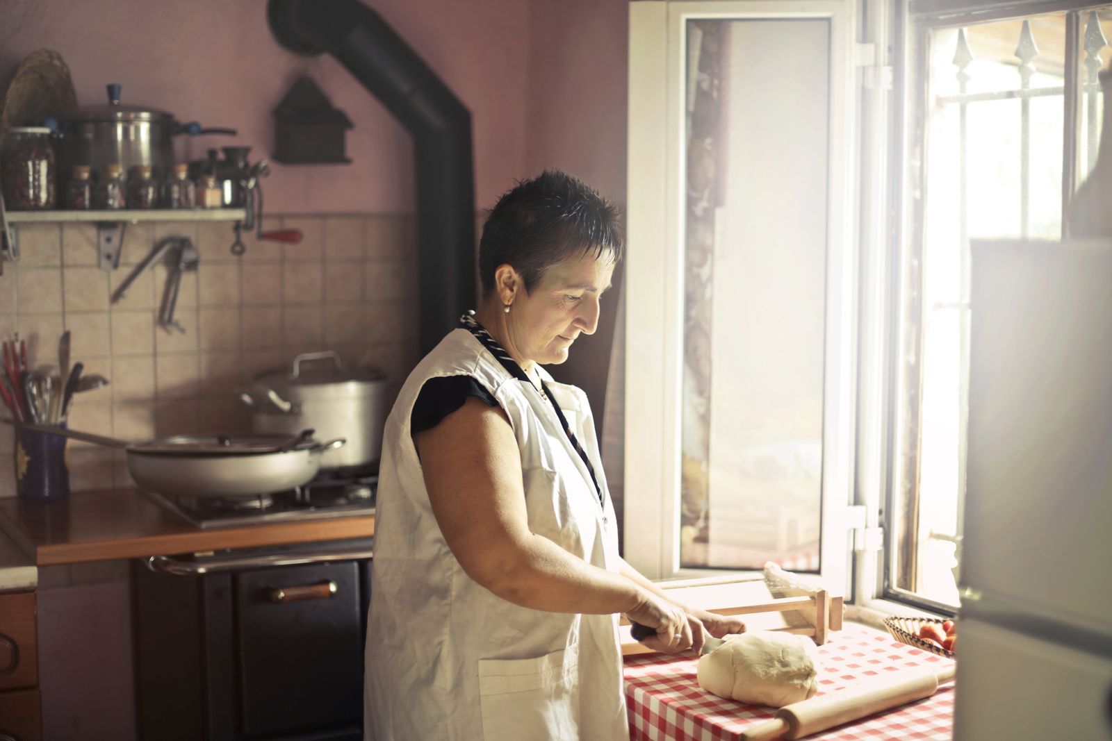 Someone kneading dough by warm window light in a rustic kitchen